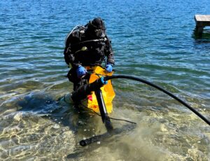 Ensuring a Reliable Water Source: A diver carefully prepares to install a submersible pump, a vital component in establishing a sustainable lake water system